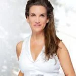 Porträtfoto einer Frau mit schulterlangem braunem Haar, die ein weißes ärmelloses Top trägt.