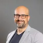 Lächelnder Glatzkopf mit Brille und grauem Blazer