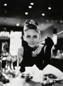 Audrey Hepburn, Frühstück bei Tiffany, ikonisches schwarzes Kleid, Perlenkette, Zigarettenspitze.