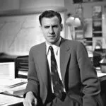 Junger Mann im Anzug aus den 50er Jahren sitzt am Schreibtisch und arbeitet.