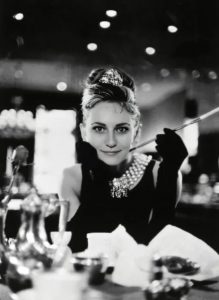 Audrey Hepburn, Frühstück bei Tiffany, ikonisches schwarzes Kleid, Perlenkette, Zigarettenspitze.