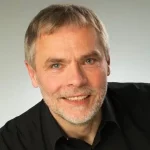 Porträt eines lächelnden Mannes mit grauem Haar und Bart