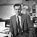 Junger Mann im Anzug aus den 50er Jahren sitzt am Schreibtisch und arbeitet.