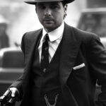 Ein Mann in einem Gangsteranzug aus den 1920er Jahren hält eine Pistole.