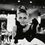 Audrey Hepburn, Frühstück bei Tiffany, ikonisches schwarzes Kleid, Perlenkette, Zigarettenspitze.